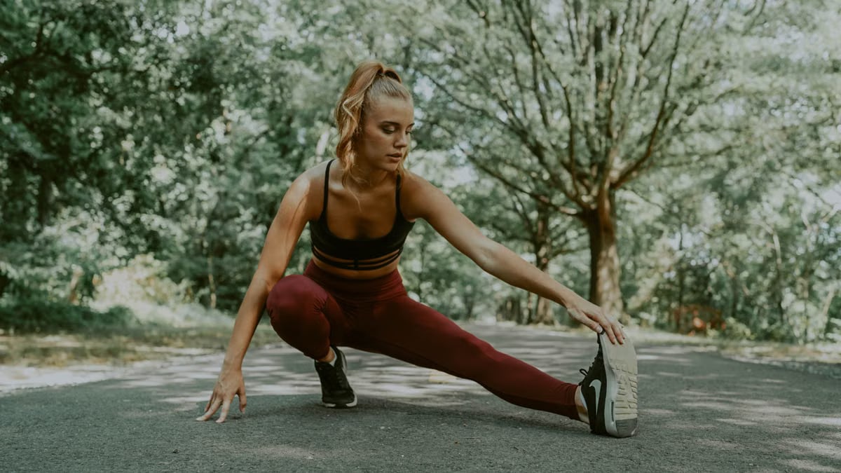 Full length of focused female athlete doing lunges forward while stretching legs in park