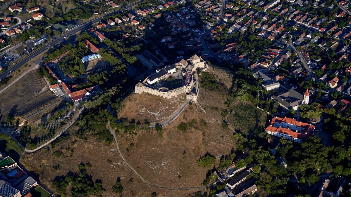 Aerial shot showcasing a historic hilltop castle with a surrounding city landscape.